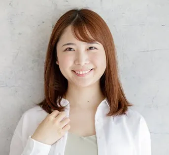 白いシャツで微笑むミディアムヘアの女性