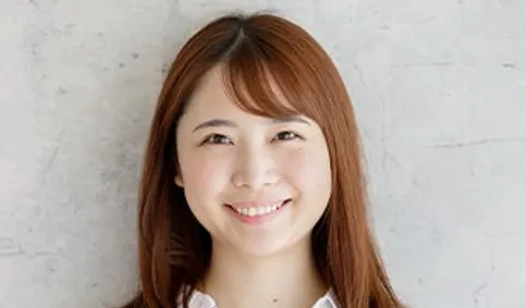 白いシャツで微笑むミディアムヘアの女性